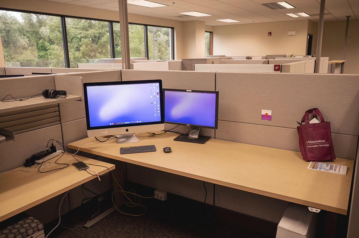 Empty desk with a branded umass amherst gift bag and a printed copy of the booklet
