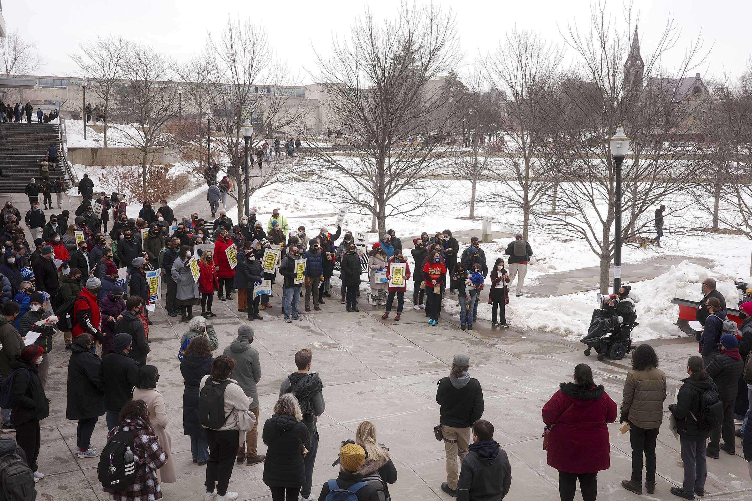 Union ralliers stand in a circle to listen to a member in a wheelchair speak